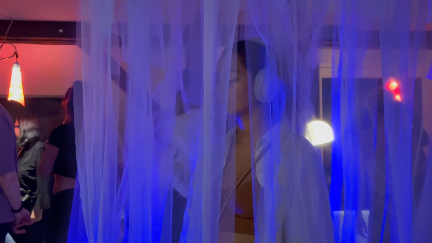 A visitor in headphones lit by warm lamps and blue