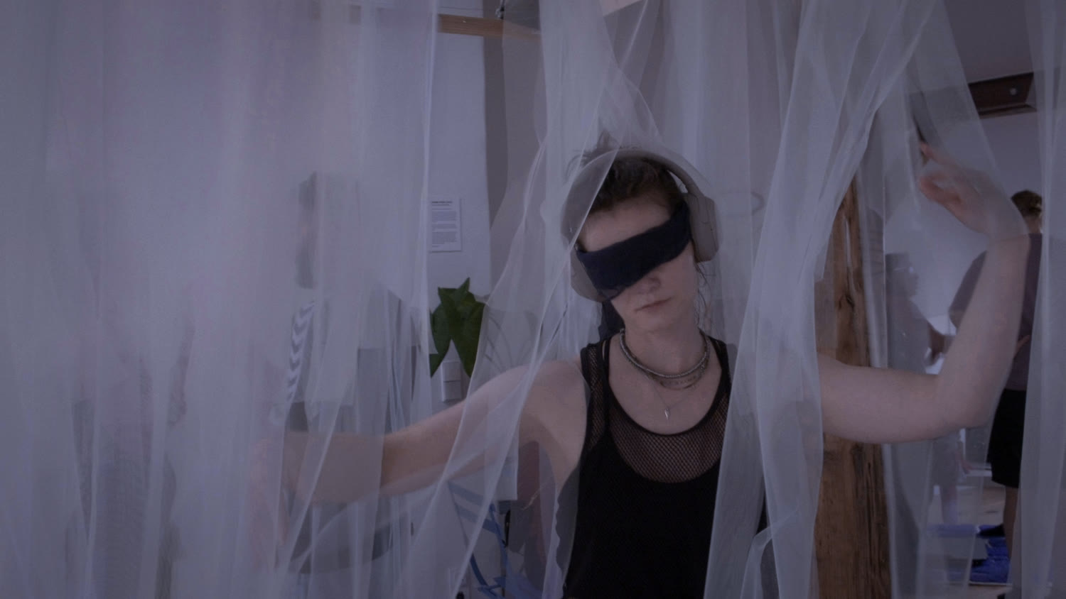 A blindfolded visitor with arms outstretched in daylight