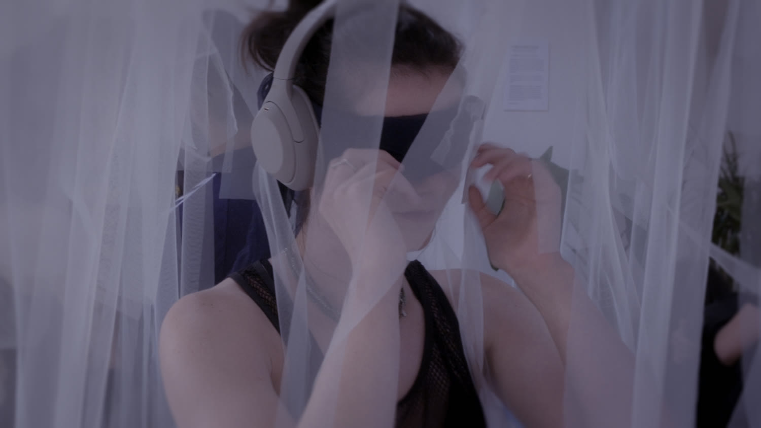 A close view of headphones and a hand against the veil