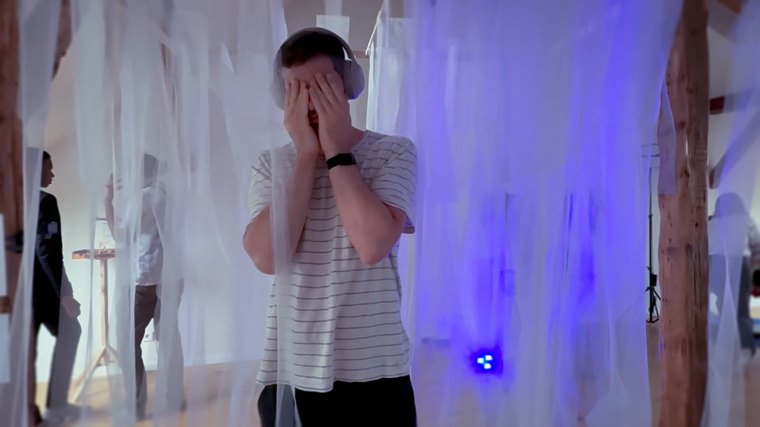A visitor overcome, hands pressed to their face, the sensor glowing nearby